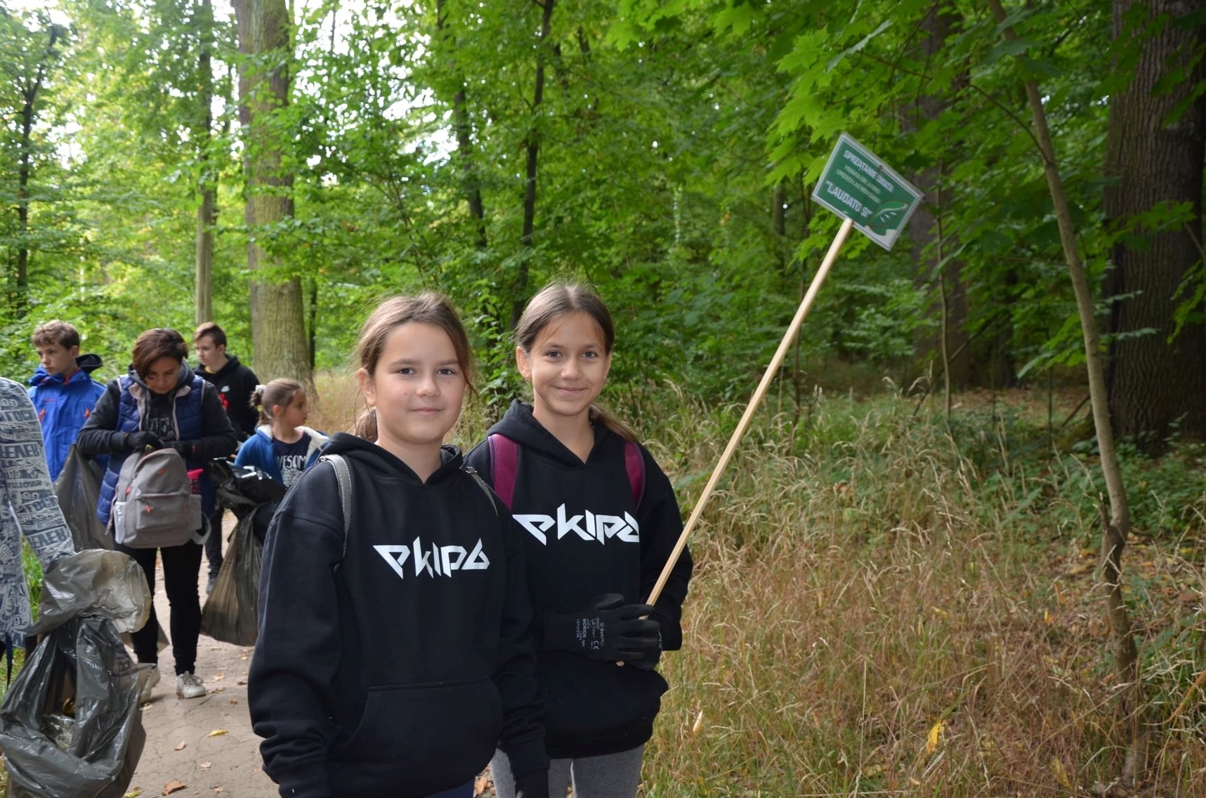 dwie dziewczynki idą sprzątać do lasu